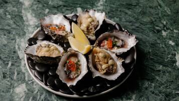 A plate of oysters with lemon wedges on a dark plate.