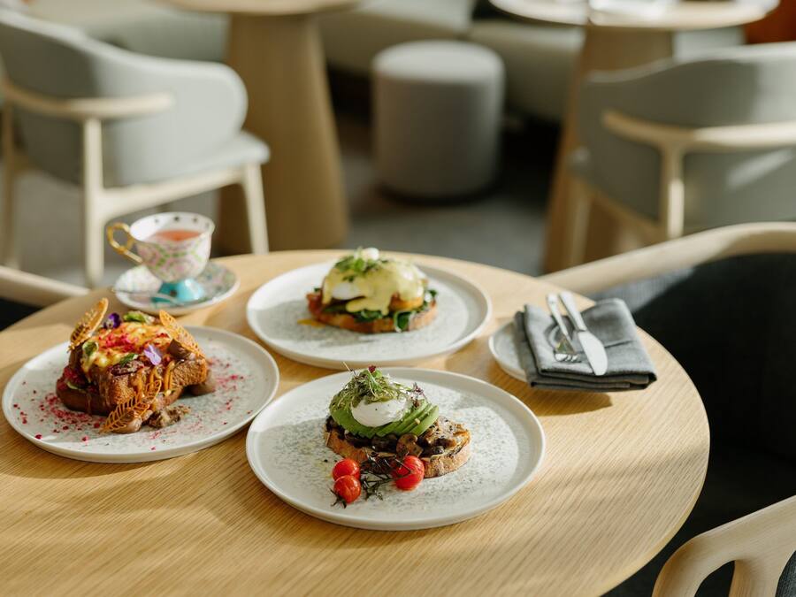 Una mesa con tres platos de comida, una taza y una servilleta doblada.