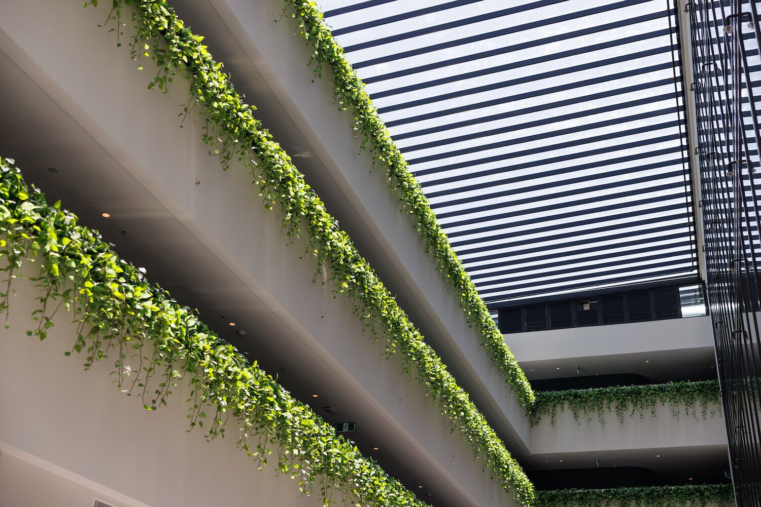 Un edificio moderno con jardines verticales en las paredes exteriores y un diseño de techo con listones.