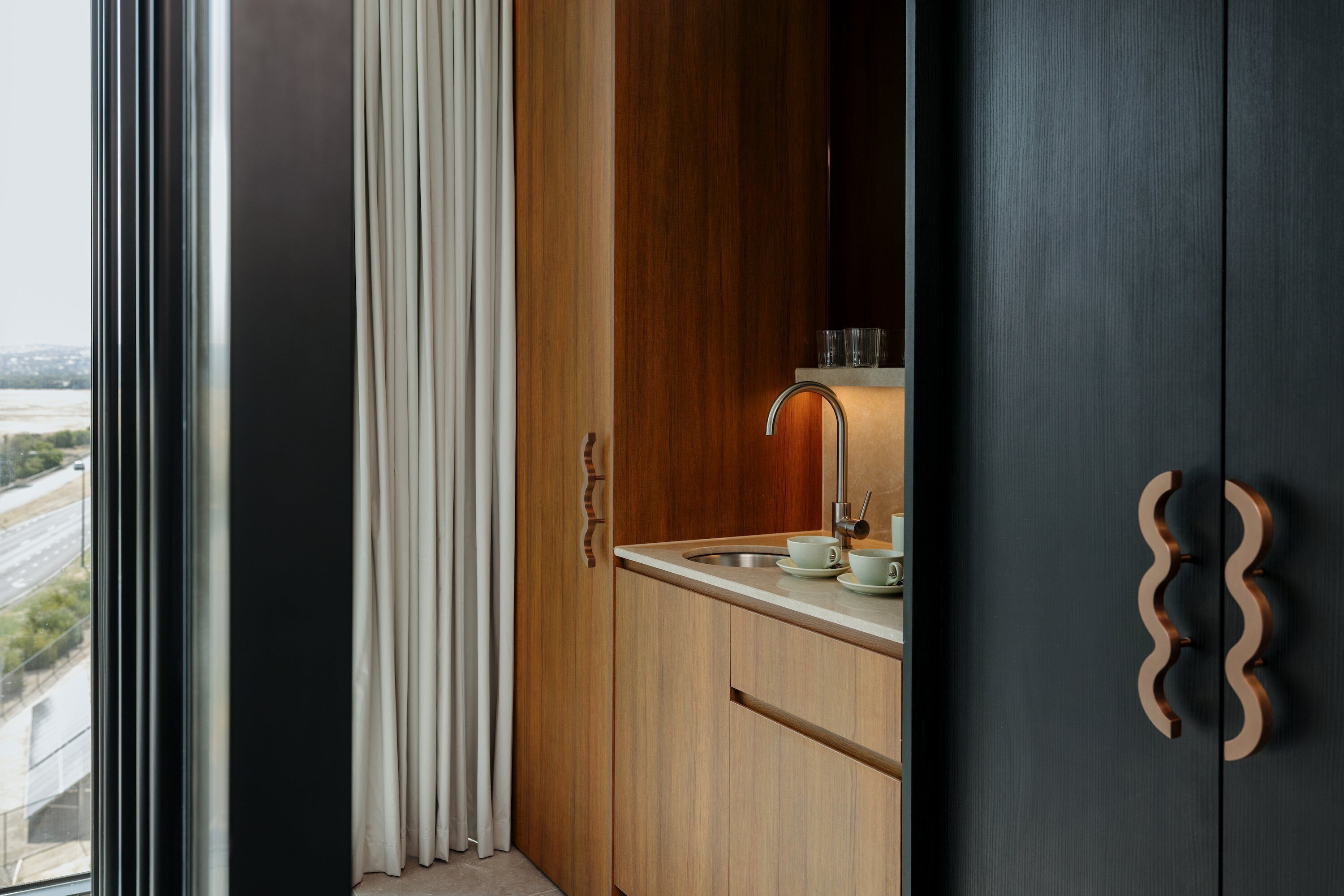 Eine moderne Küche mit großem Fenster, Holzschränken und einer Spüle.