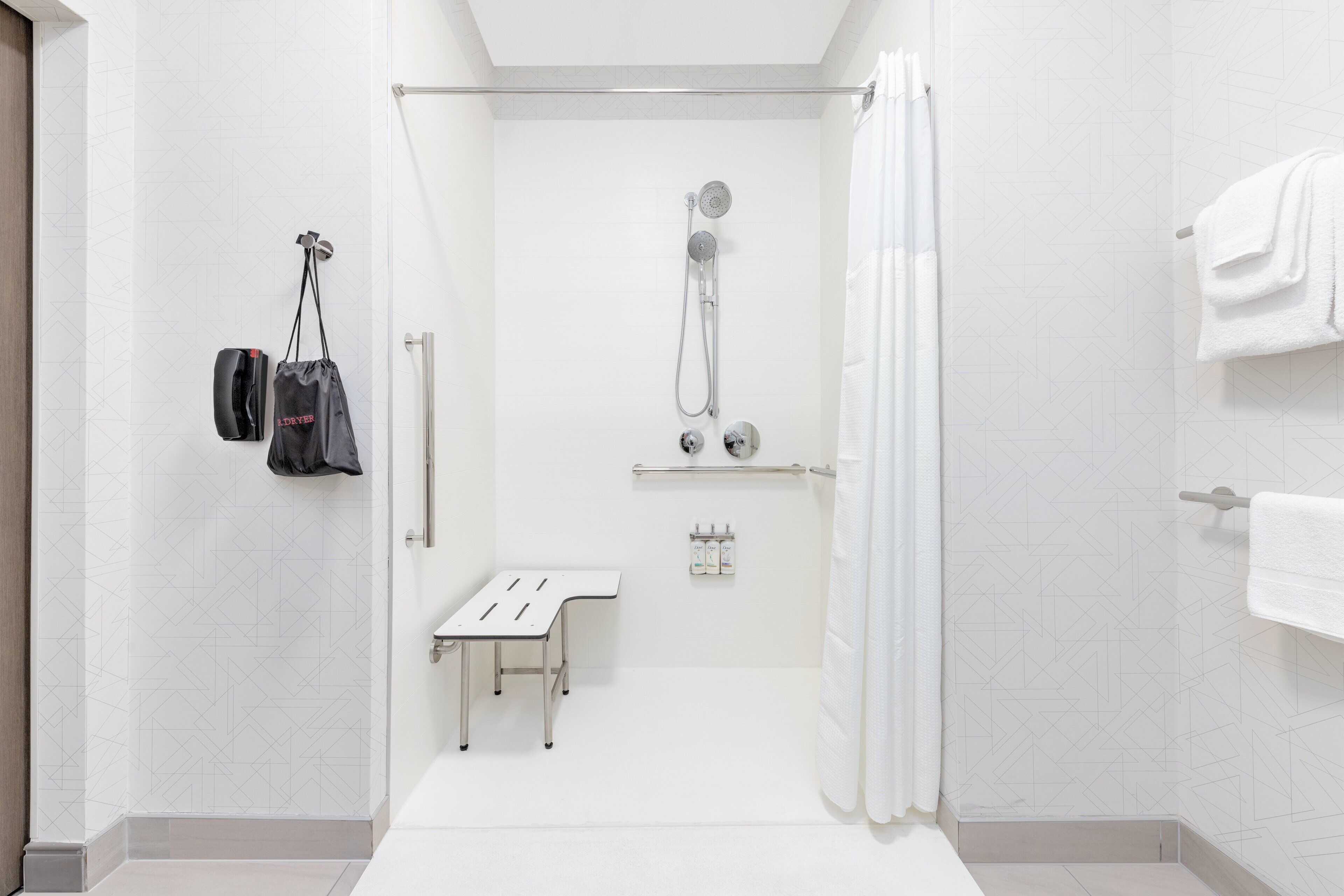 A modern bathroom with a shower, a bench, and a towel rack.