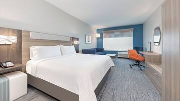 Una habitación de hotel con cama, escritorio, silla, ventana y espejo.