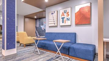 A modern lobby with a blue sofa, yellow chairs, and two small tables.