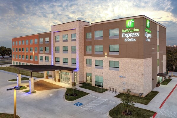 A Holiday Inn Express & Suites building with a brick facade, multiple windows, and a covered entrance area. - Holiday Inn Express & Suites Austin Airport East by IHG (Austin)