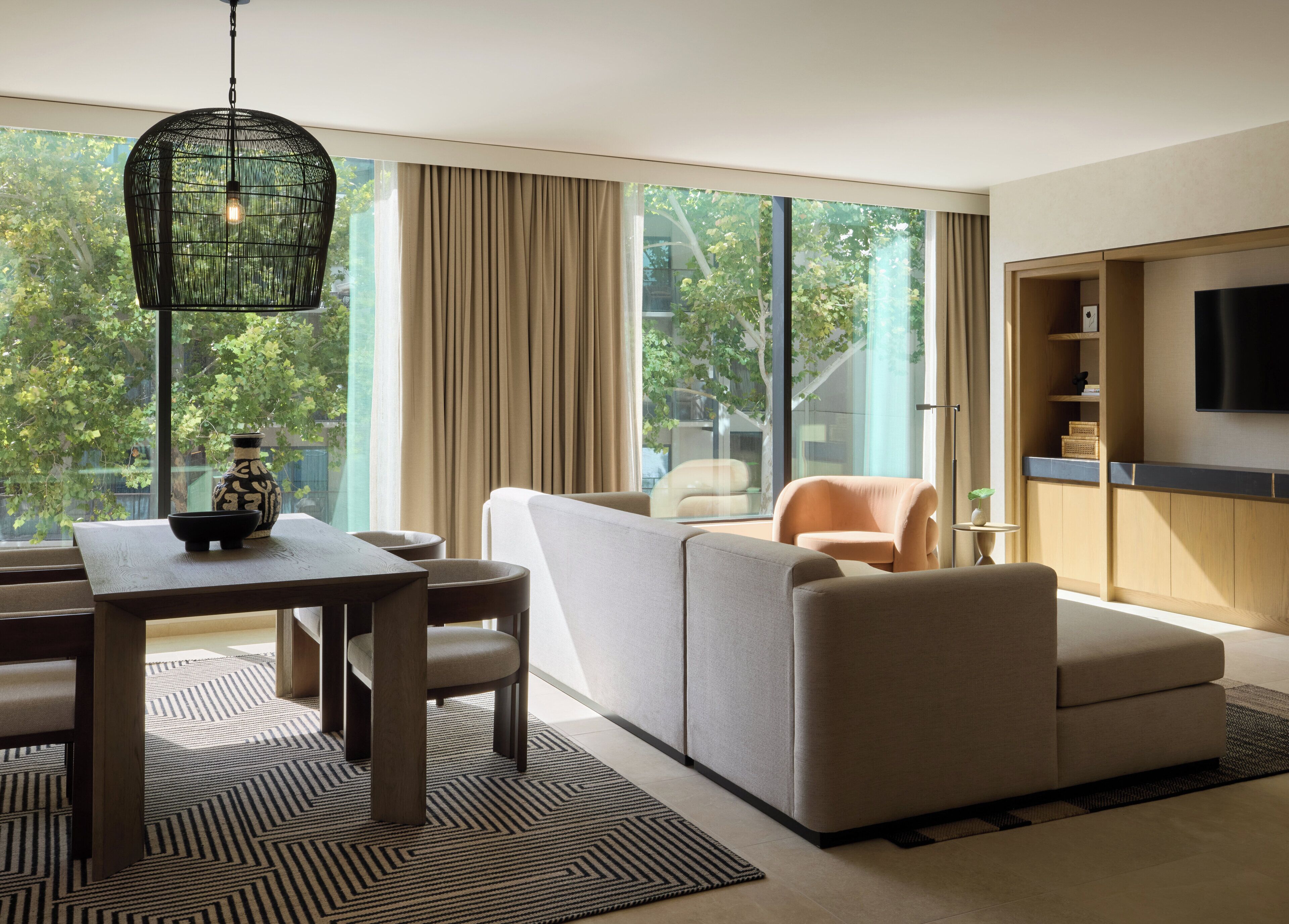 A modern living room with a sofa, chairs, a dining table, and a TV.