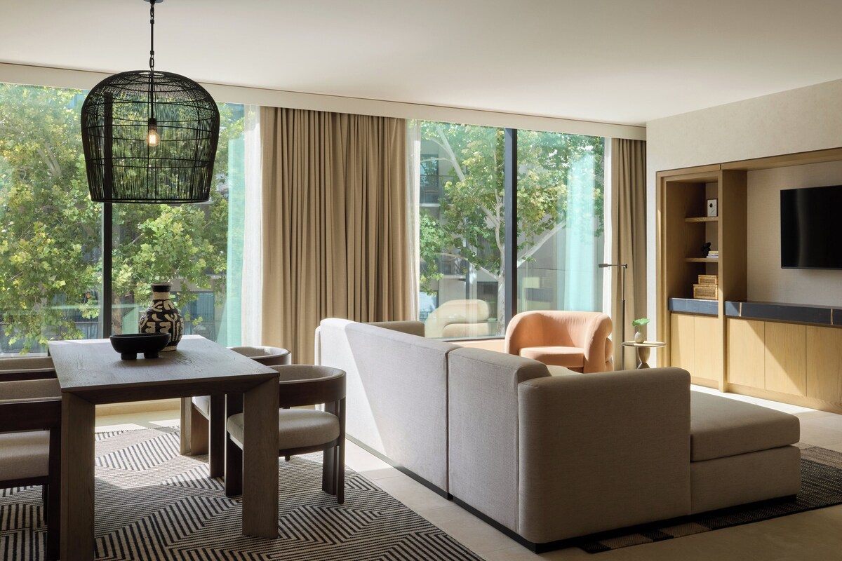 A modern living room with a sofa, chairs, a dining table, and a TV.
