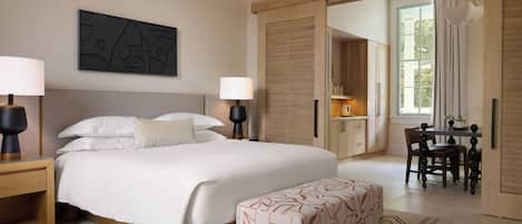 Una habitación de hotel moderna con una cama grande, lámparas de noche, un escritorio con una silla y vistas al exterior a través de una puerta corredera.