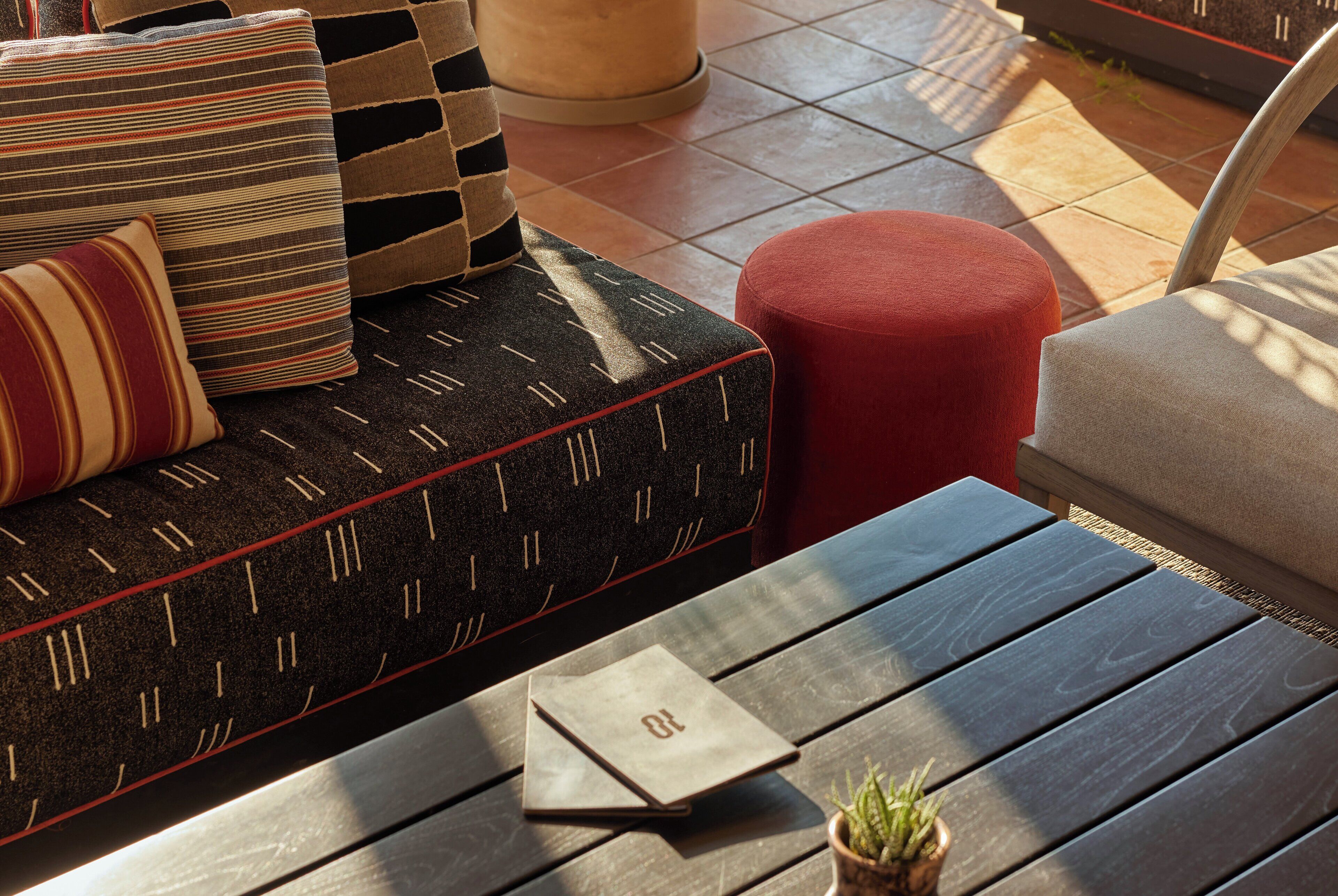 A modern outdoor seating area with a sofa, ottoman, and table.