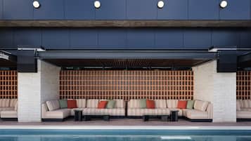 A modern outdoor seating area with a pool, featuring a brick wall and wooden slats.