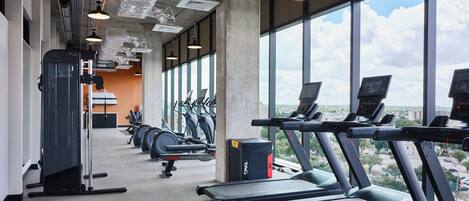 Un gimnasio con cintas de correr, bicicletas estáticas y máquinas de pesas.