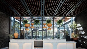 A modern reception area with a central counter, potted plants, and a sloped ceiling with exposed beams. - Kimpton Santo San Antonio - Riverwalk by IHG (San Antonio)