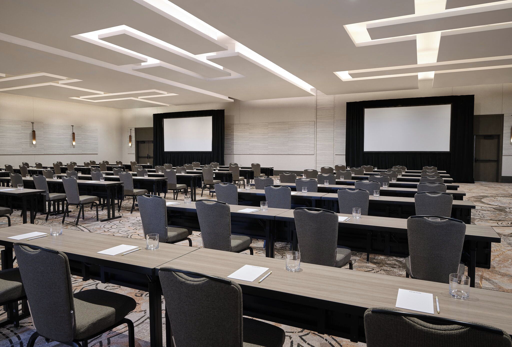 Une salle de conférence dotée de plusieurs tables et chaises, de grands écrans et d’un éclairage moderne.