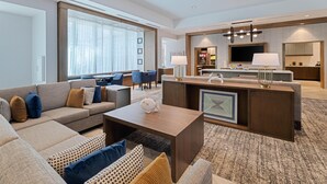 A modern hotel room with a living area featuring a sofa, coffee table, and a kitchen area with a counter and seating. - Drury Inn & Suites Destin Miramar Beach (Miramar Beach)