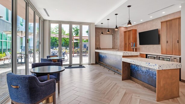 A modern kitchen with a large island, wooden cabinets, and a flat-screen TV. - Drury Inn & Suites Destin Miramar Beach (Miramar Beach)