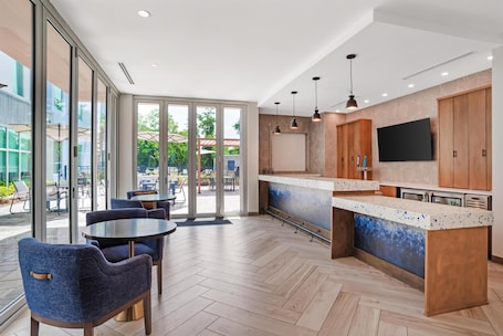 A modern kitchen with a large island, wooden cabinets, and a flat-screen TV.