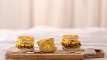 Tres sándwiches de desayuno sobre una tabla de madera.
