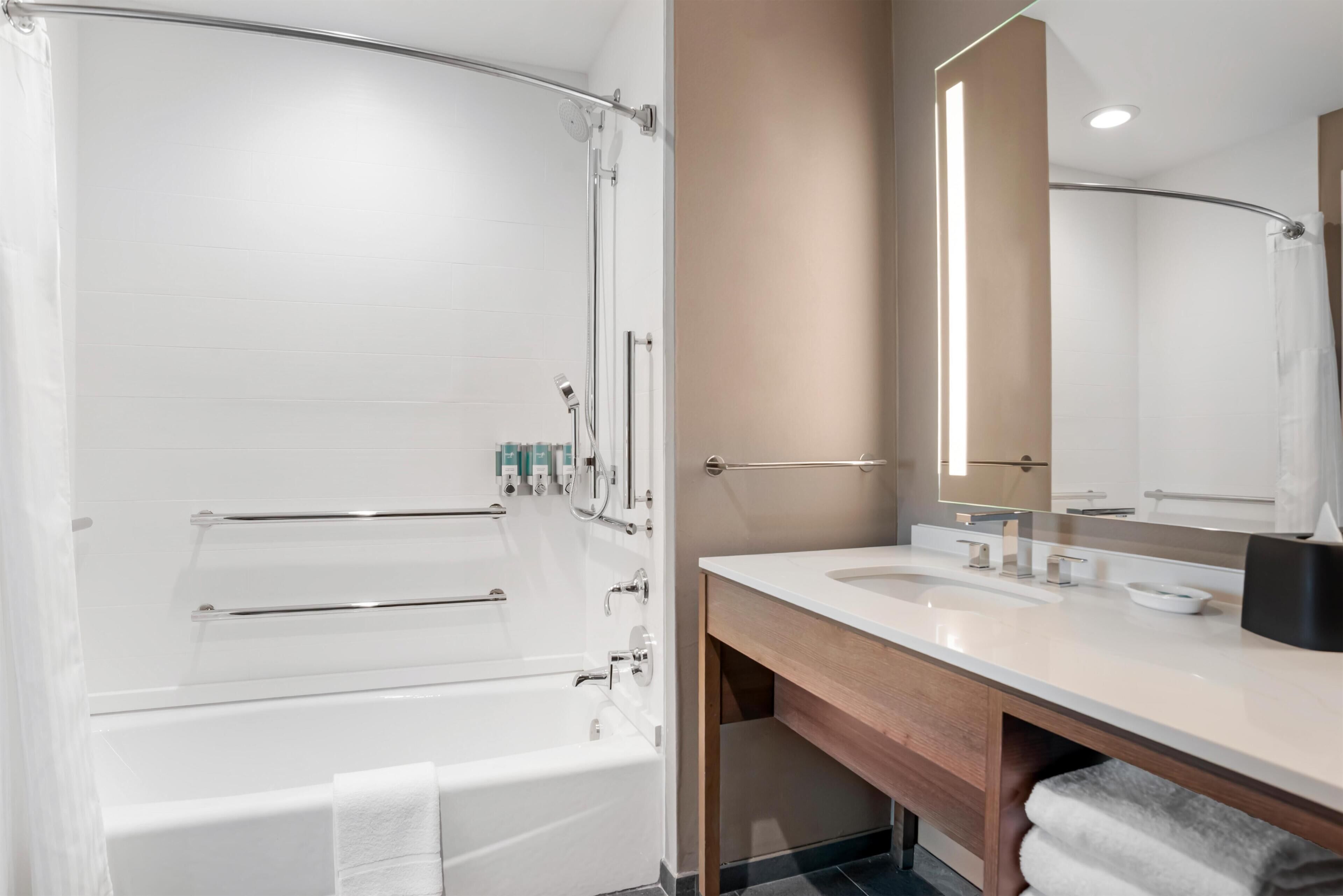 A modern bathroom with a bathtub, a vanity with a mirror, and a shower area.