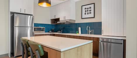 A modern kitchen with a central island, stainless steel appliances, and pendant lighting.