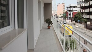 Un balcone con una pianta in vaso, un furgone giallo per le consegne e una vista della strada con edifici.