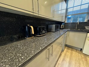 A modern kitchen with granite countertops, stainless steel appliances, and a window with blinds. - 1-Bedroom Flat in Islington! (Greater London)