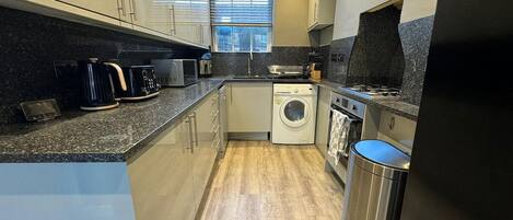 A compact kitchen with a washing machine, a microwave, and a stove.