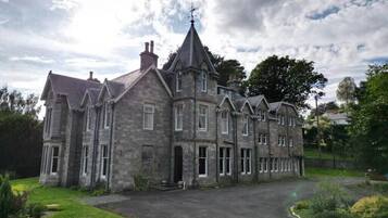 A large, historic stone building with multiple chimneys and a prominent tower.