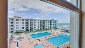 Ett hotell med flera pooler, utsikt över stranden och en stor byggnad med balkonger.
