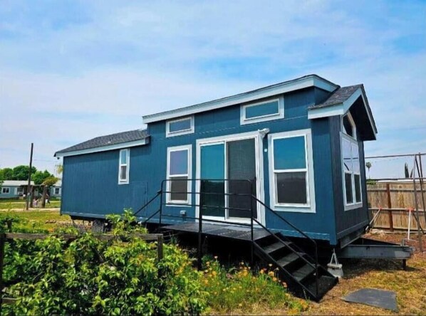 Une maison de plain-pied à l’extérieur bleu, avec des boiseries blanches et un porche à l’avant doté d’un escalier.