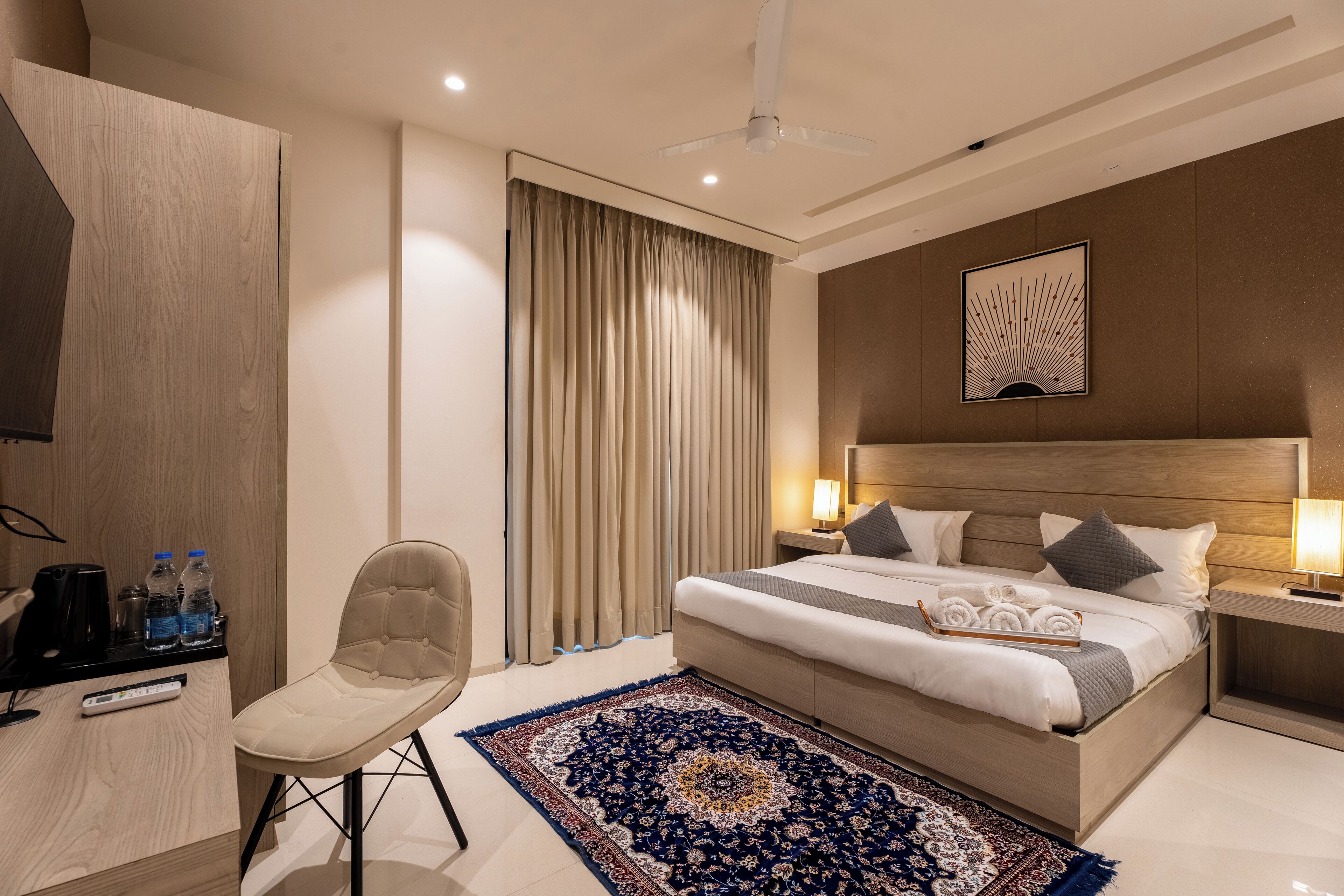 Une chambre d’hôtel moderne équipée d’un lit, de tables de chevet, d’une chaise, d’un bureau avec une télécommande et d’un tapis décoratif.