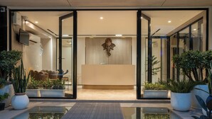 A reception area with a modern design, featuring a reception desk, seating area, and potted plants.