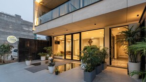 A modern building with a glass entrance, outdoor seating area, and potted plants.