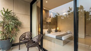 A modern bedroom with a large bed, a potted plant, and a chair by the window.