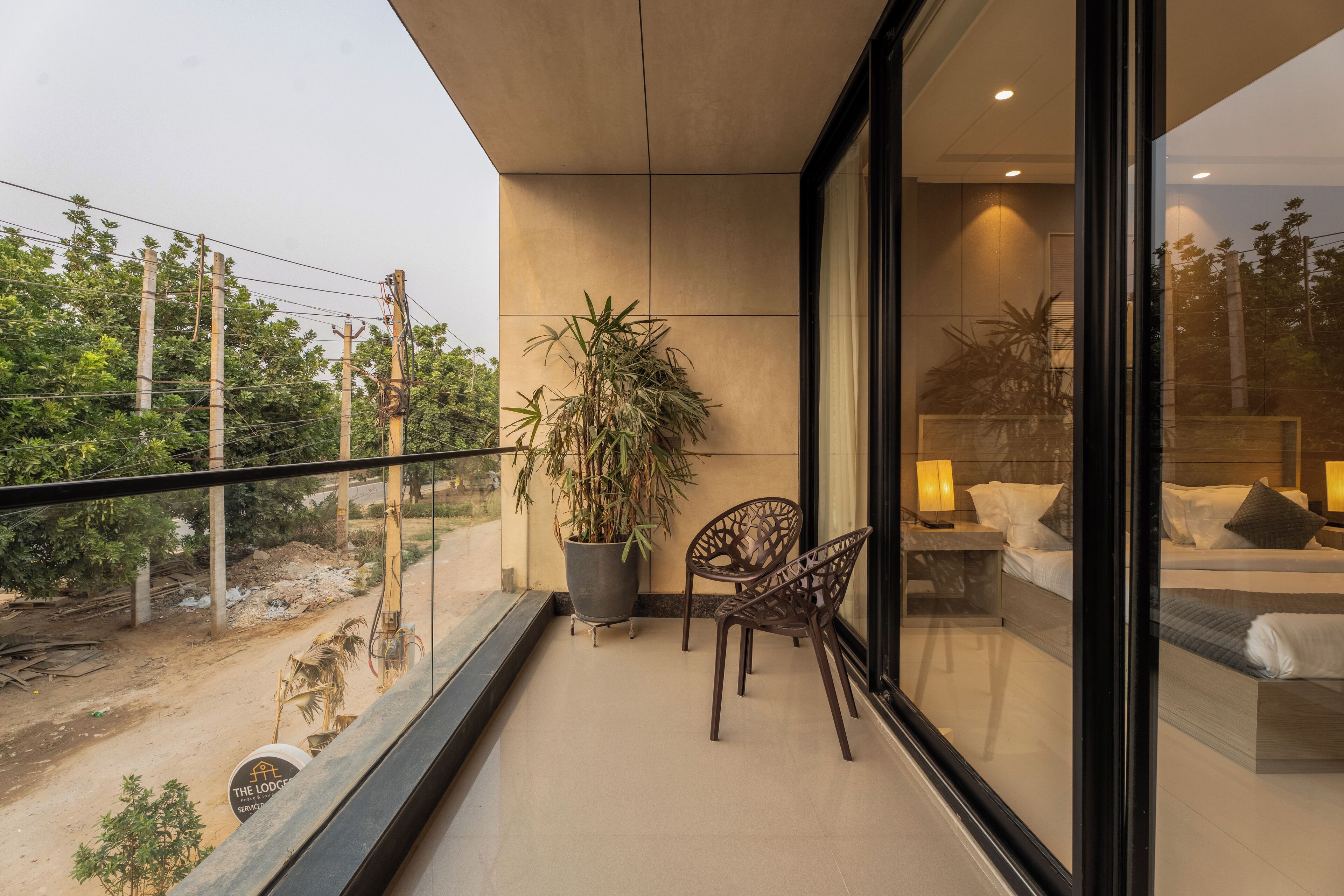 Ein Balkon mit Topfpflanze, Stuhl und Bett mit Kissen und Nachttisch.