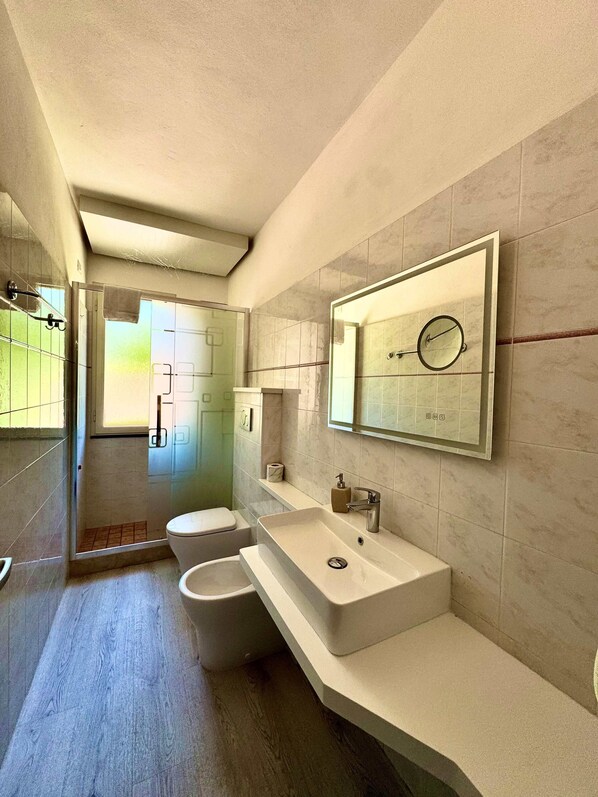 Une salle de bain moderne avec un grand miroir, un lavabo et des toilettes.