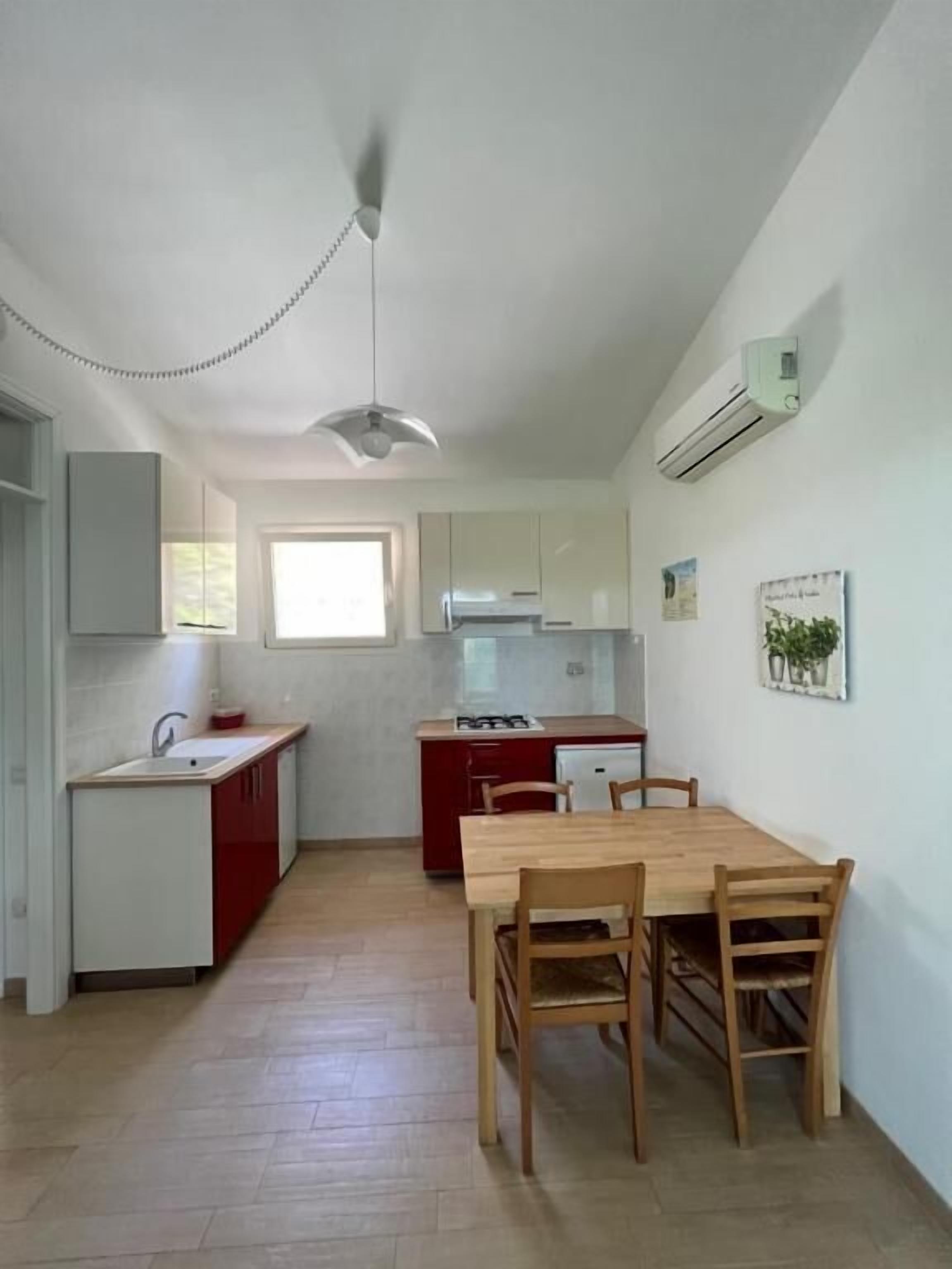 Cocina compacta con comedor, paredes blancas y ventana.