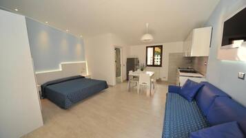 Un espace de vie compact comprenant un lit, un coin repas et une kitchenette.