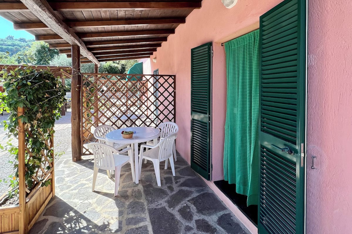 A covered patio with a stone floor, a table with chairs, and a wooden pergola.