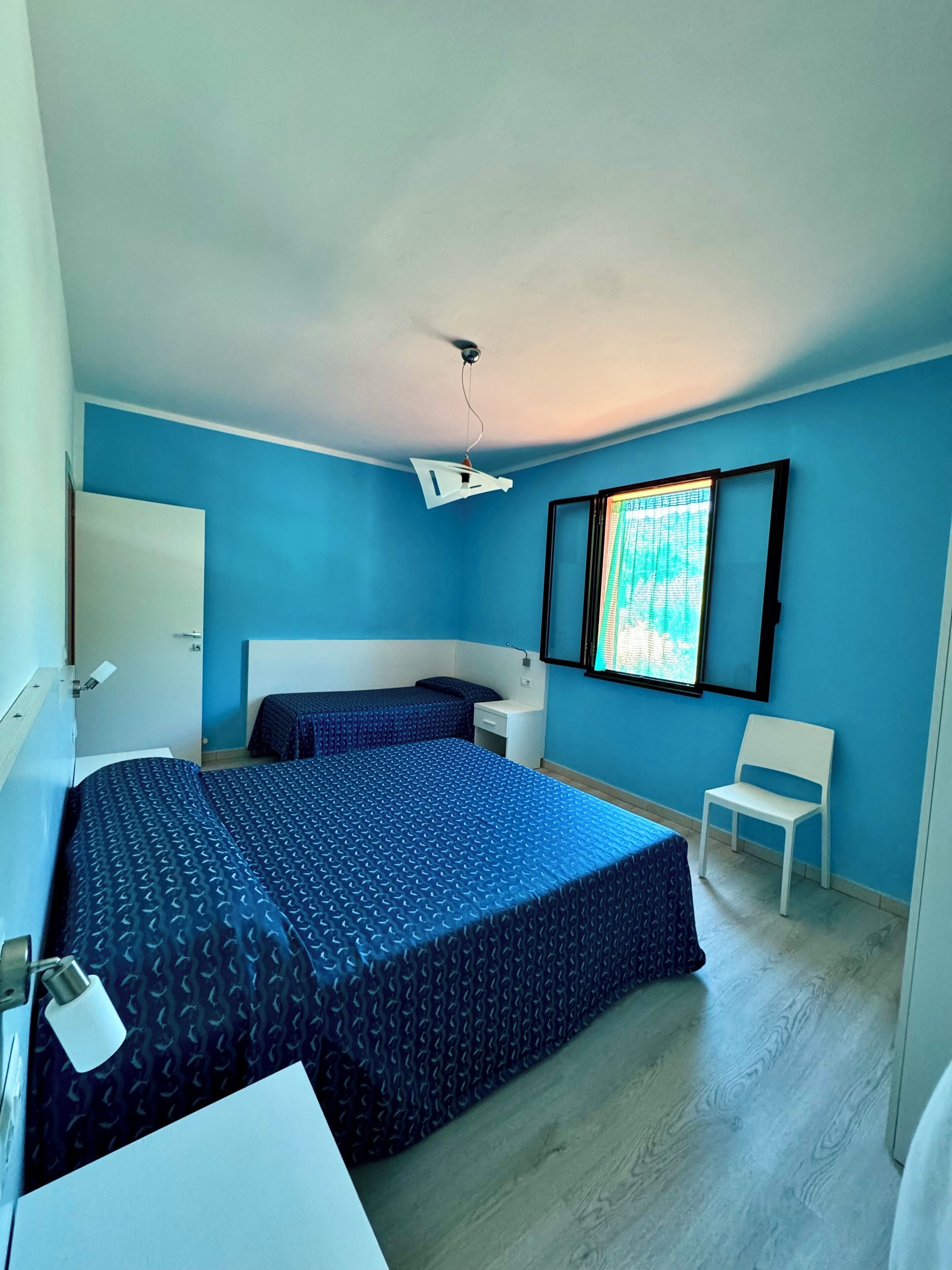 Ein Schlafzimmer mit einem Bett, einem Schreibtisch, einem Stuhl und einem Deckenventilator.