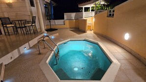A swimming pool with a metal ladder, a small sink, and a chair area with a table and chairs.