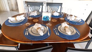 A round dining table with blue placemats, white napkins, and clear glassware.