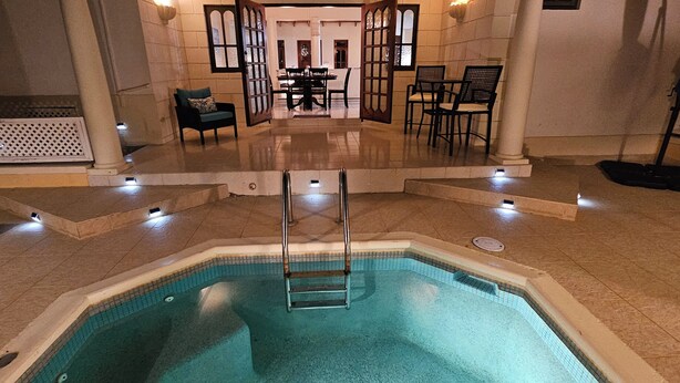 An indoor swimming pool with a clear view of the adjacent dining area and seating.