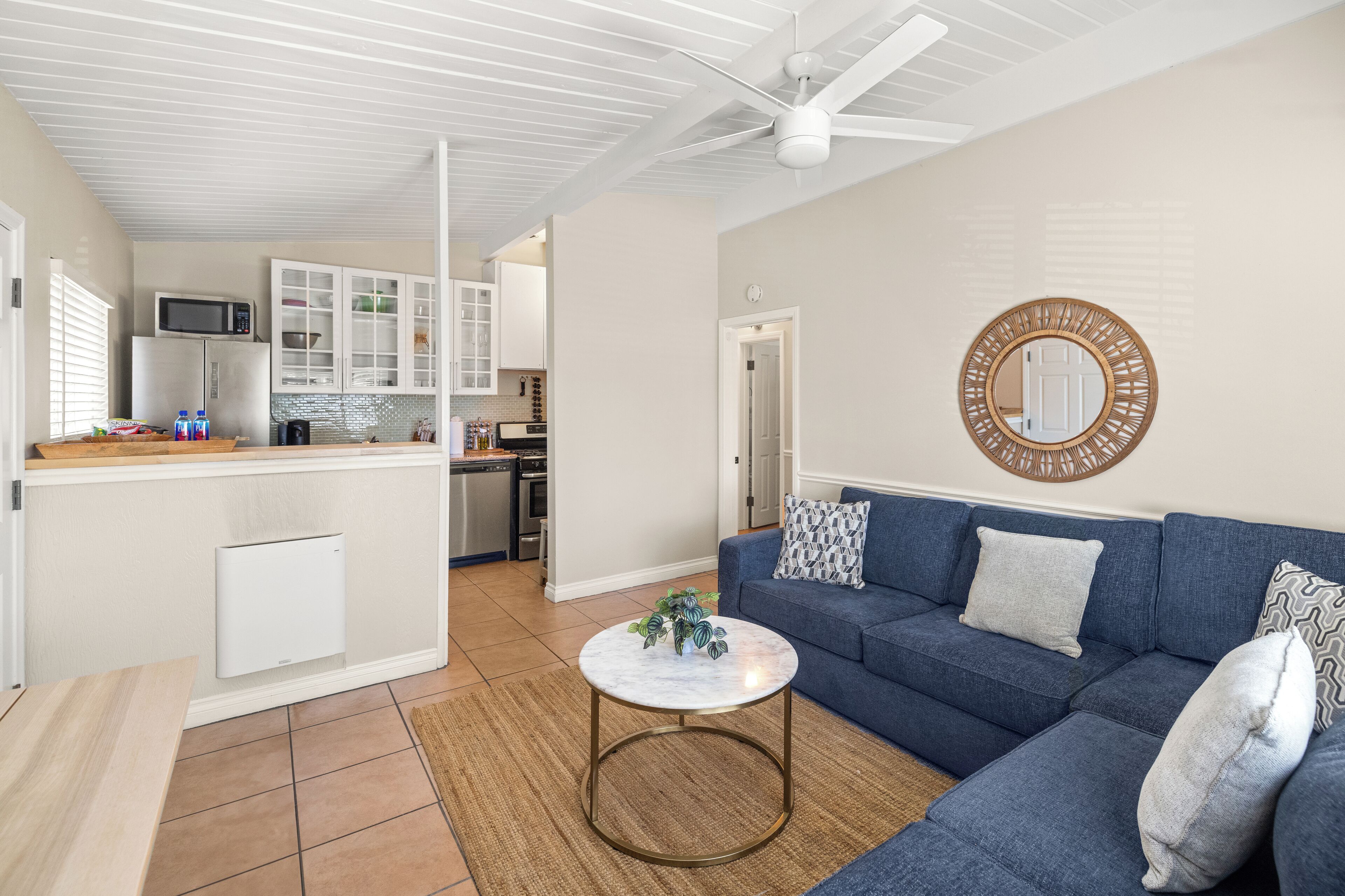 A modern living room with a blue sofa, a round coffee table, and a kitchen in the background.