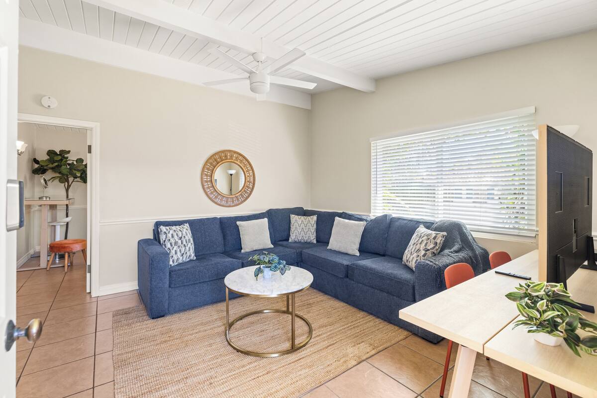 A living room with a sectional sofa, a round coffee table, and a television.