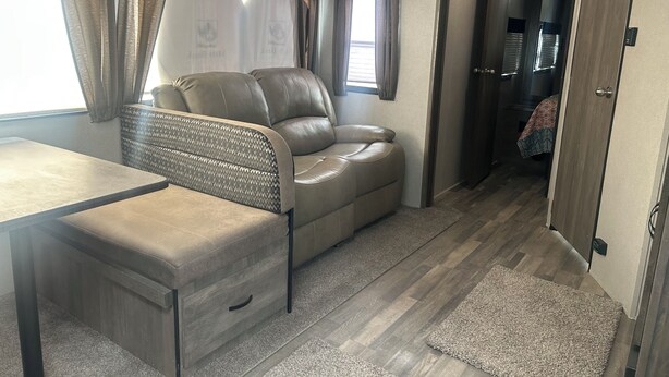Un espacio habitable compacto con un sofá, una mesita y un banco con almacenamiento.