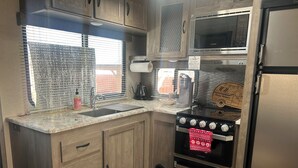 Una cocina compacta con un fregadero, estufa y microondas.