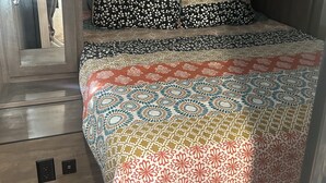 Un dormitorio con edredón estampado, cabecera y suelo de madera.
