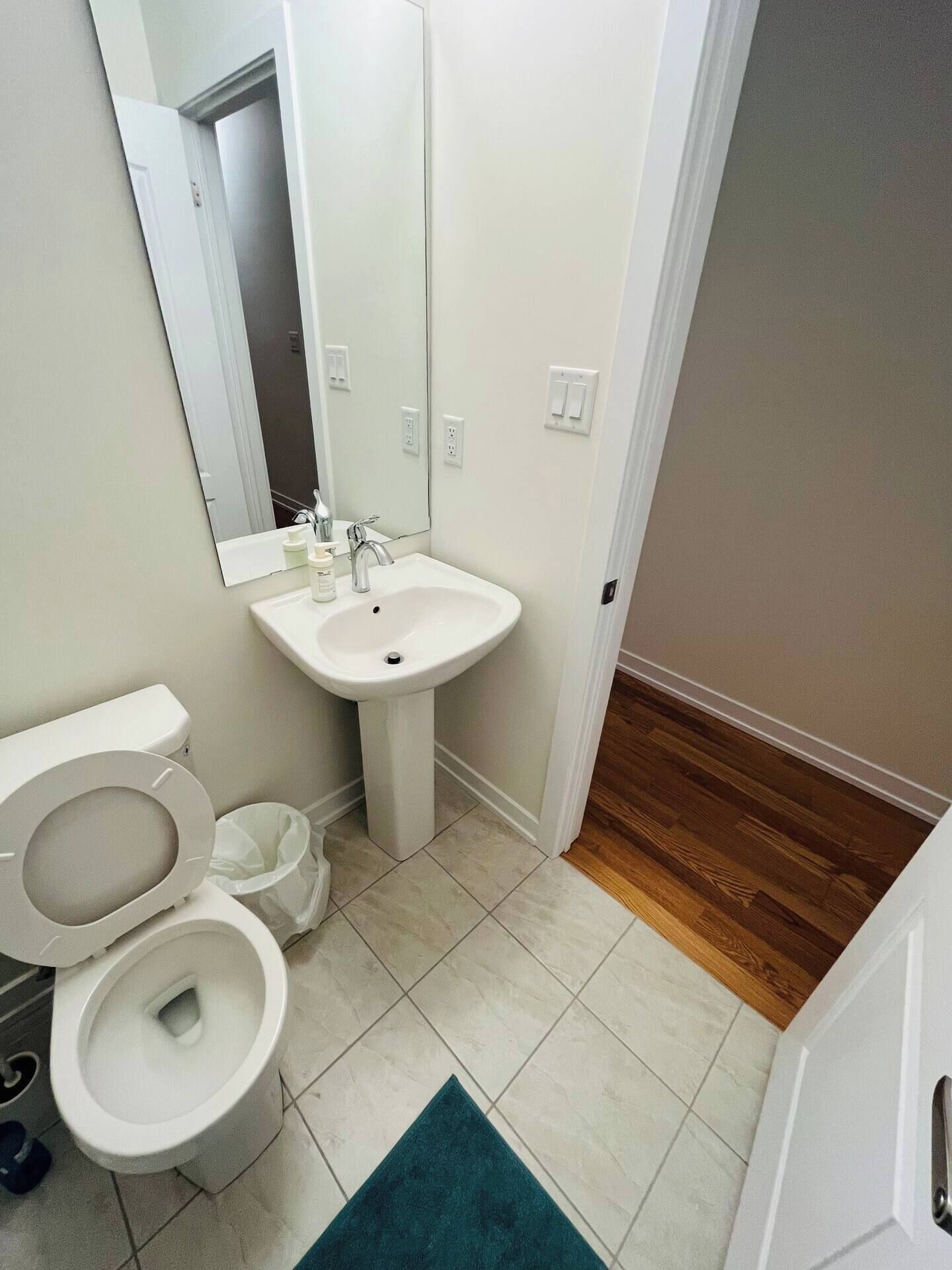 A bathroom with a toilet, sink, and mirror.