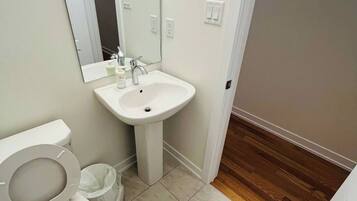 A bathroom with a toilet, sink, and mirror.