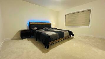 A bedroom with a bed, nightstands, a lamp, and a window with blinds.