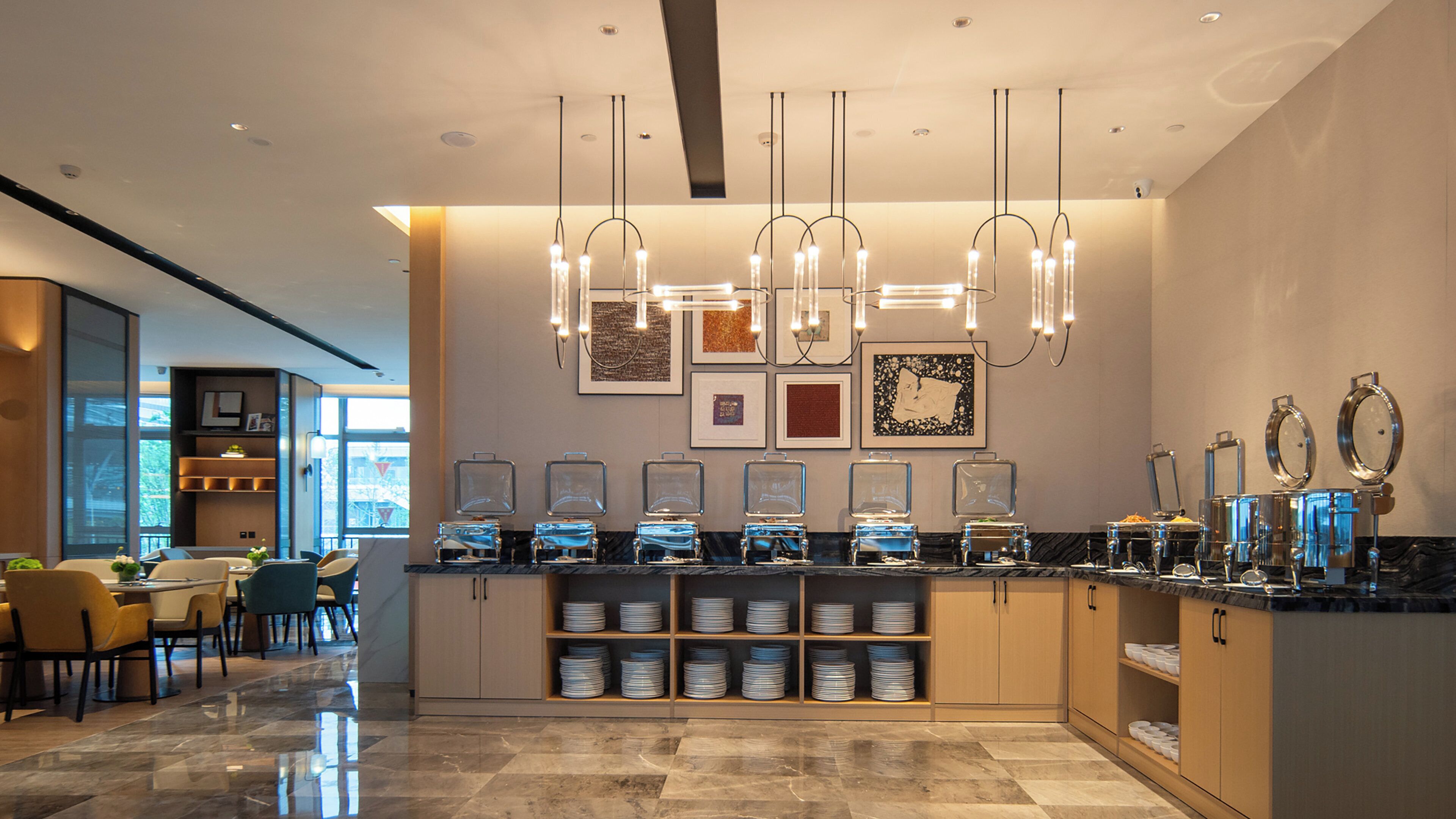 A modern hotel lobby with a reception desk, seating area, and a wall with framed artwork.
